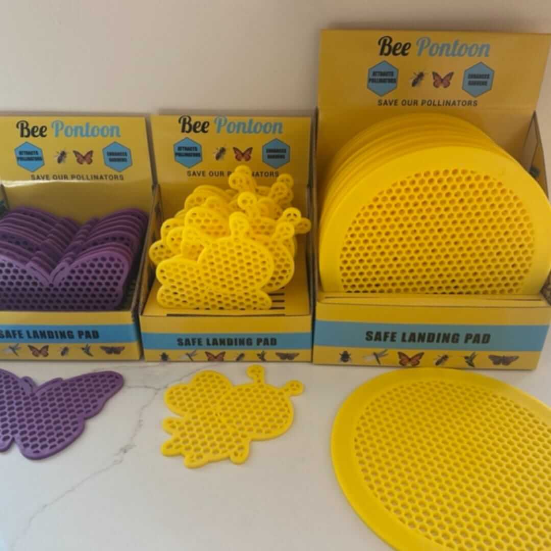 Yellow and purple 'Bee Pontoon' safe landing pads with packaging on a white surface.